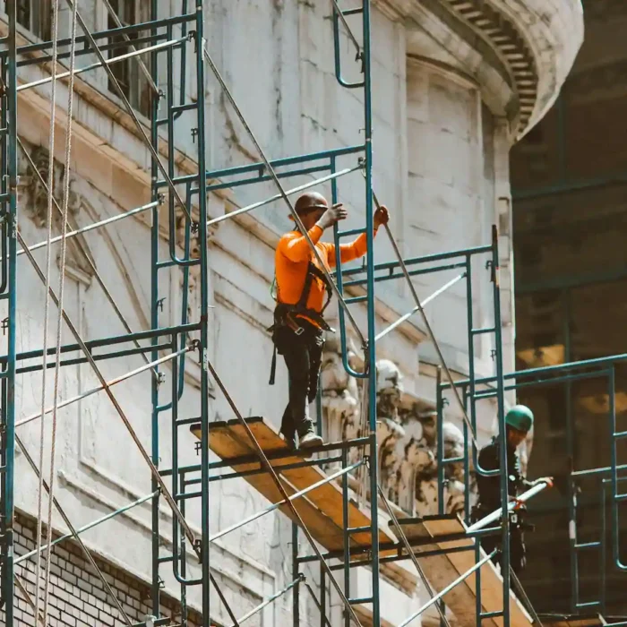 Construction workers assembling scaffolding near a downtown building project